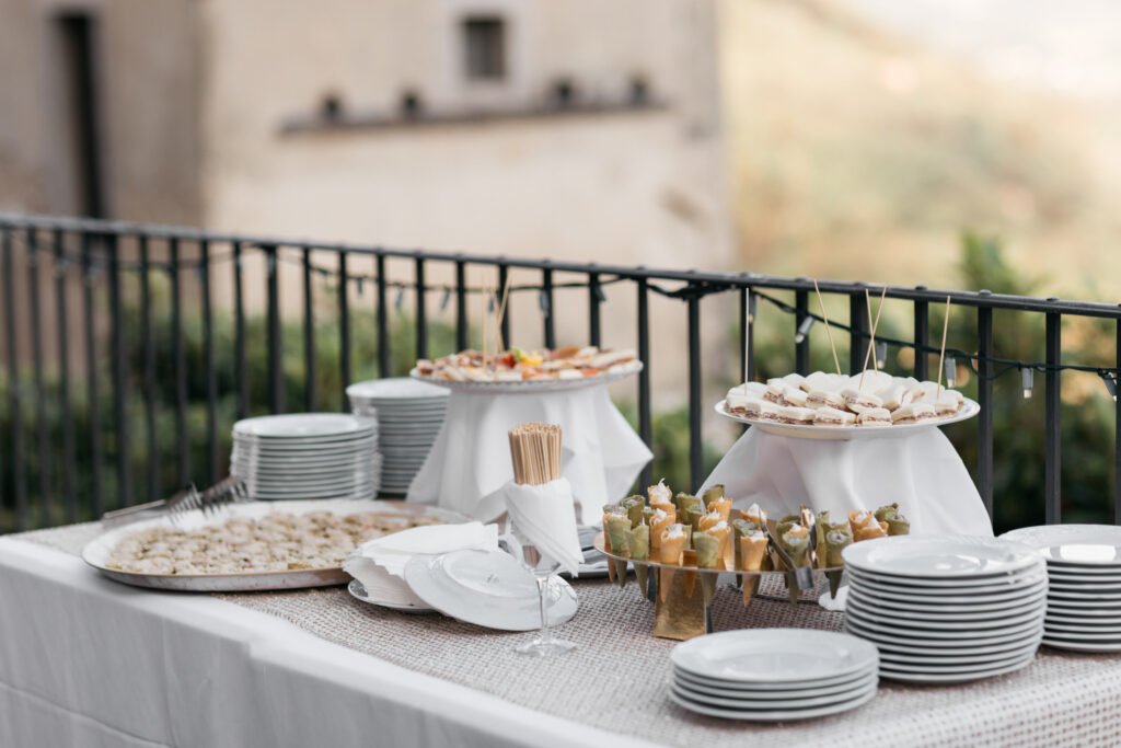 Refined buffet setup for a destination wedding reception on a terrace overlooking the Italian countryside