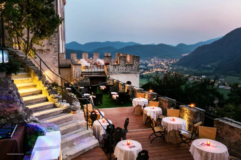 Elegant wedding reception with round tables and floral centerpieces inside a historic castle venue in northern Italy