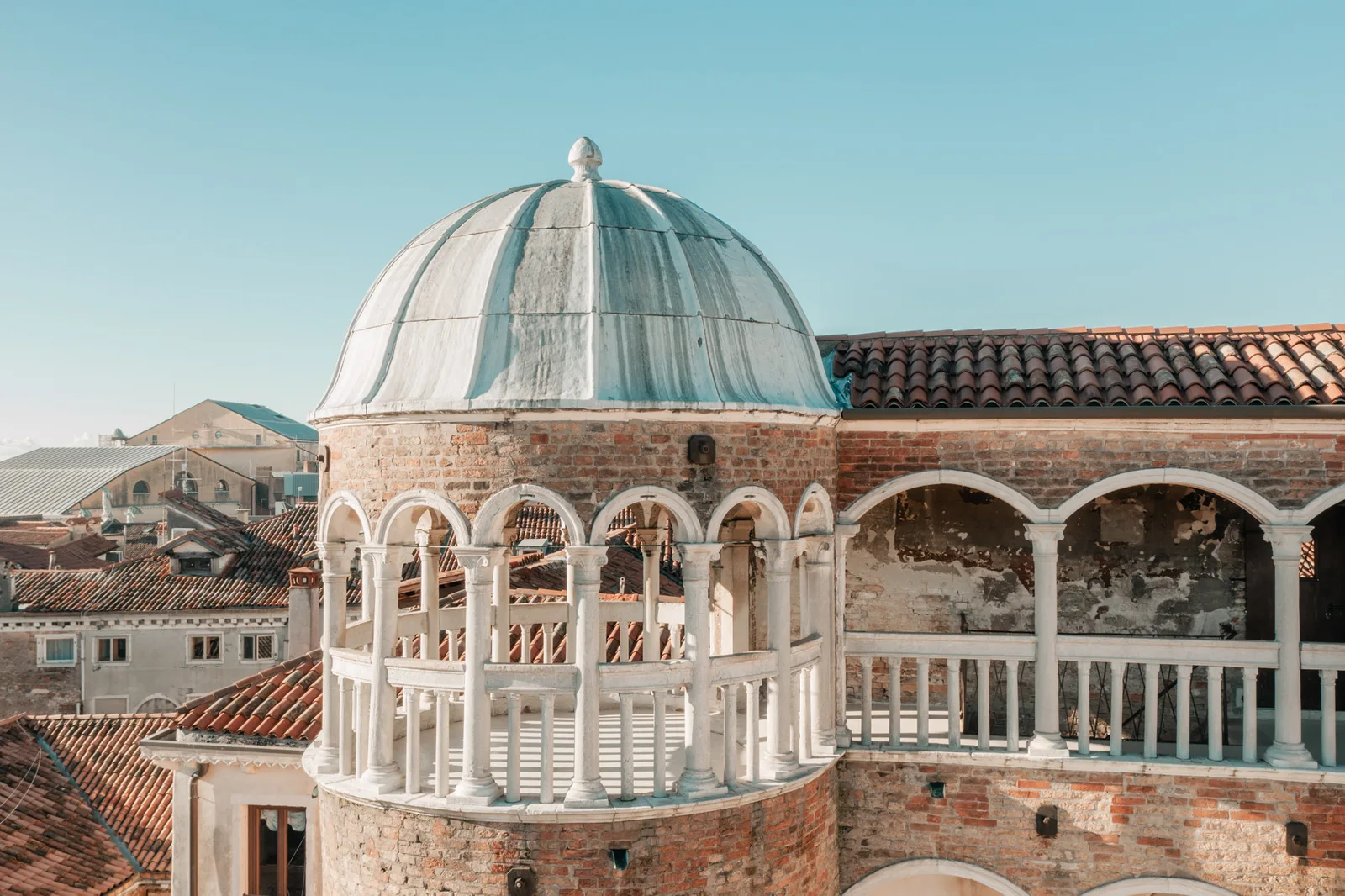 The dome and the curved loggia at the top of the tower, under a clear blue sky