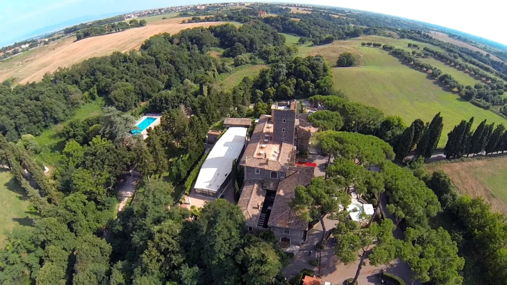 Aerial view of the castle surrounded by a large green park, umbrella pines and the Roman countryside