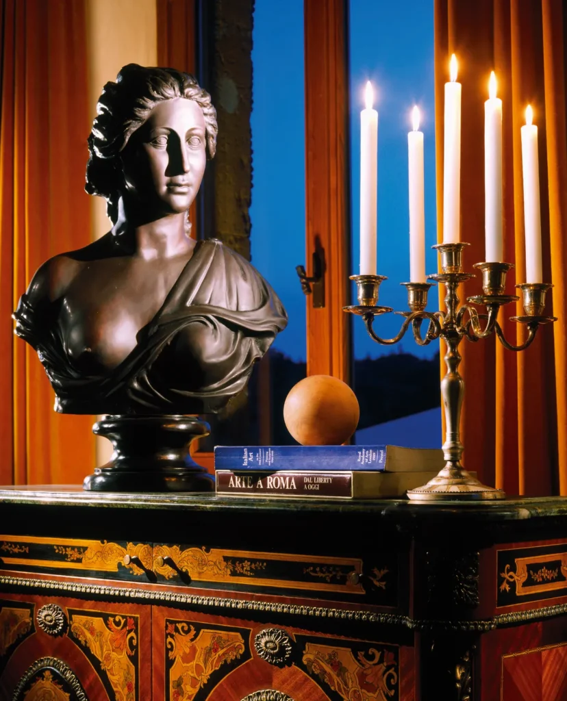 A bronze bust and lit candles on an antique cabinet inside the castle