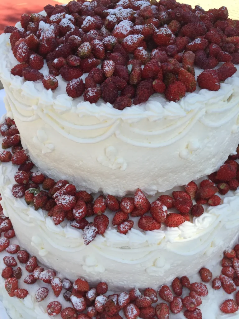 A white tiered wedding cake covered with wild strawberries