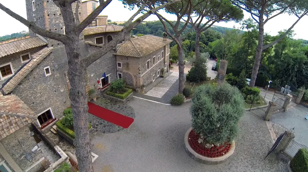 Aerial view of the castle courtyard with an olive tree, stone buildings and umbrella pines