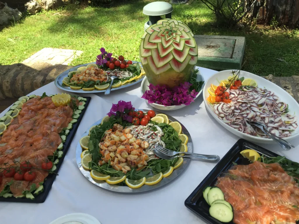 A garden buffet with seafood, cured meats, salads and a carved watermelon