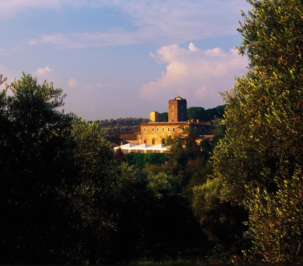A medieval castle seen from afar at sunset, rising above the green hills of the Roman countryside
