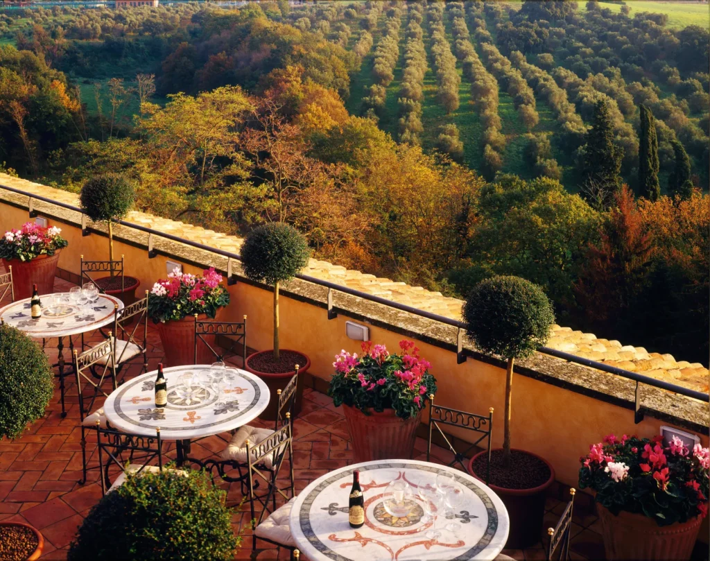 A terrace with mosaic tables overlooking olive groves and autumn hills in the Roman countryside