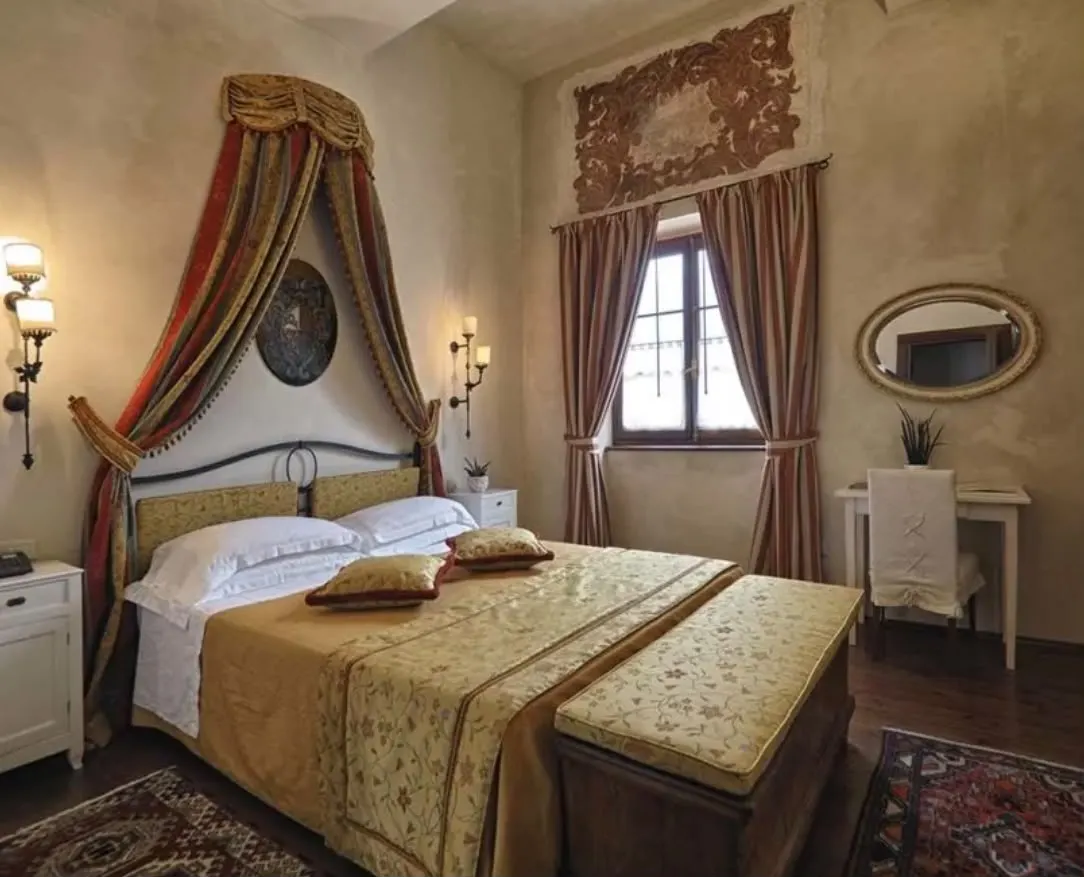A superior room in the castle with a canopy bed, painted walls and antique furniture