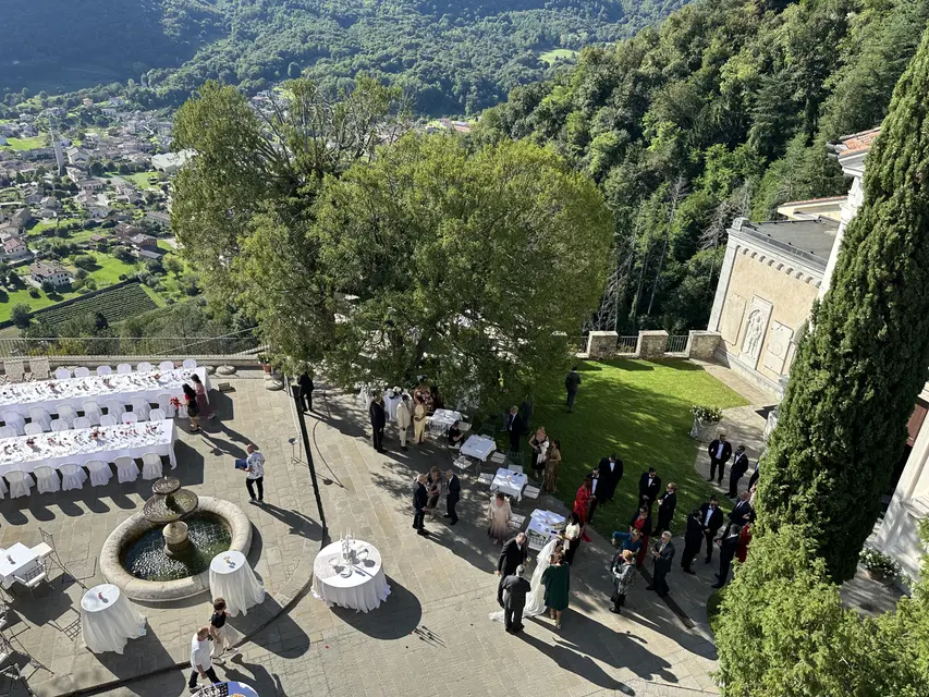 Guests at an aperitif in the castle courtyard, seen from above, with the valley and the village below