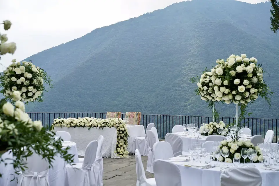 A wedding reception terrace with white flowers and the green mountains of the Veneto behind