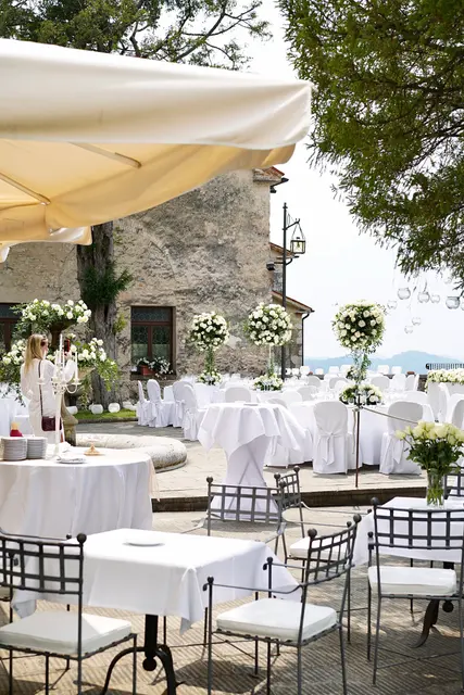 Tables with white flowers under umbrellas on a castle terrace overlooking the valley