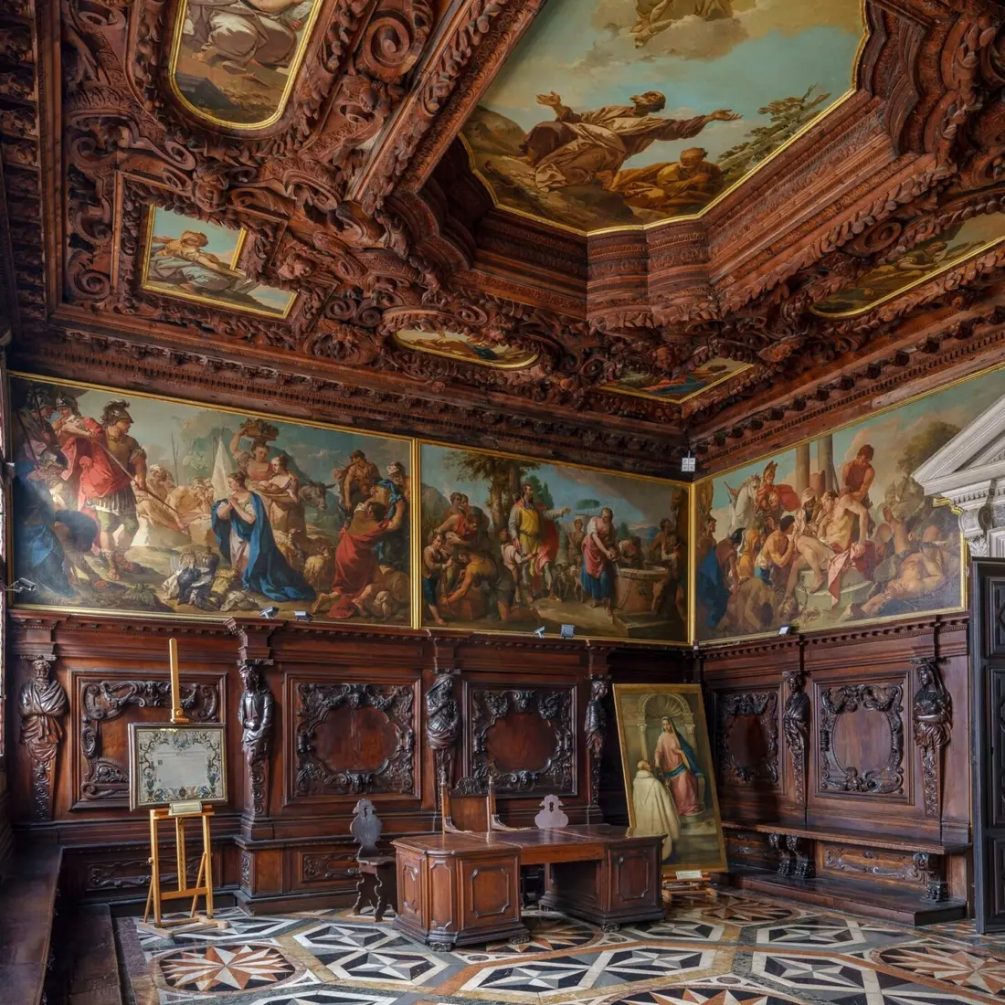 The Archive Hall, with carved wooden walls and a cycle of paintings under a carved ceiling