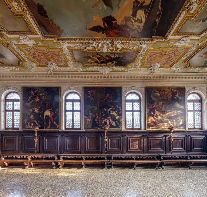 The Chapter Hall, with a painted ceiling, large canvases and carved wooden benches