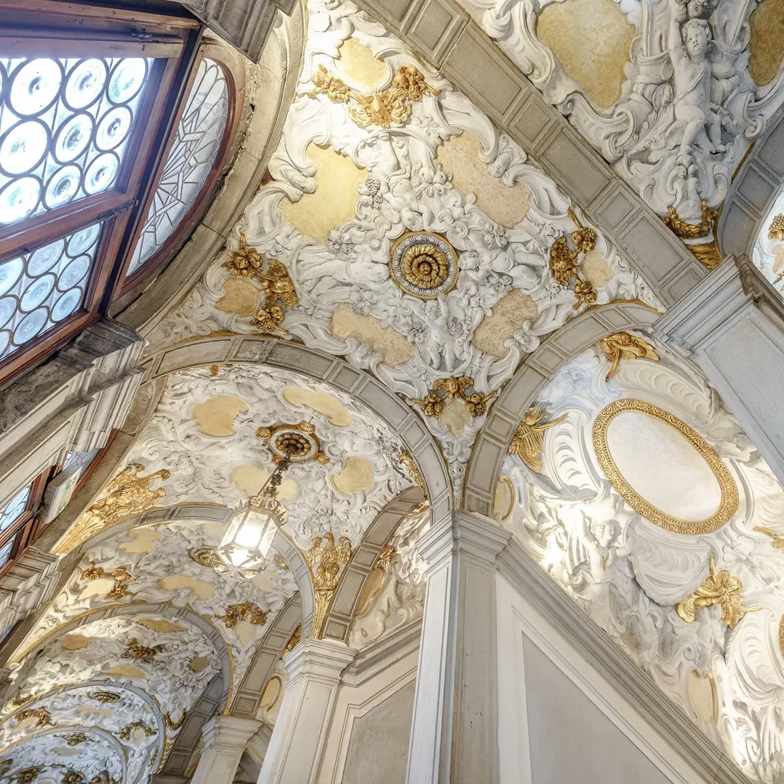 The vaulted ceiling of the grand staircase, decorated with white and gold stucco
