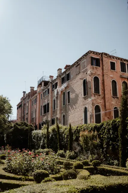 The brick facade of the palace rising above the garden hedges