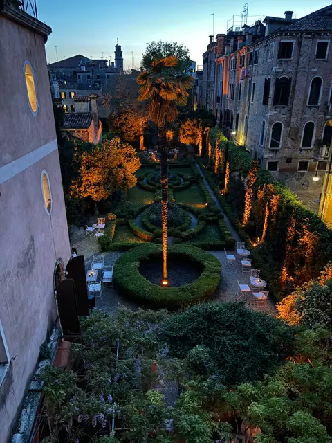 The garden lit at night, seen from an upper window, with warm lights among the hedges