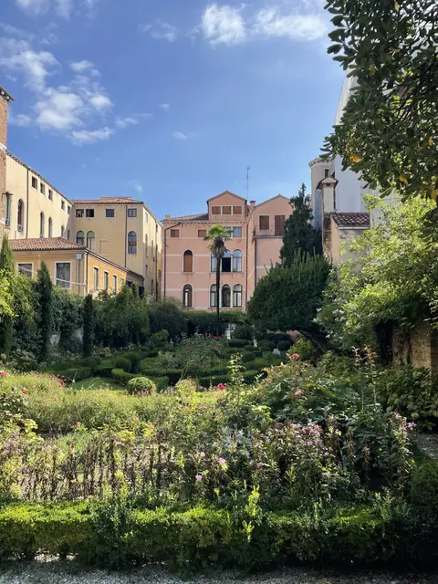 Roses and greenery in the palace garden, with pastel Venetian houses behind