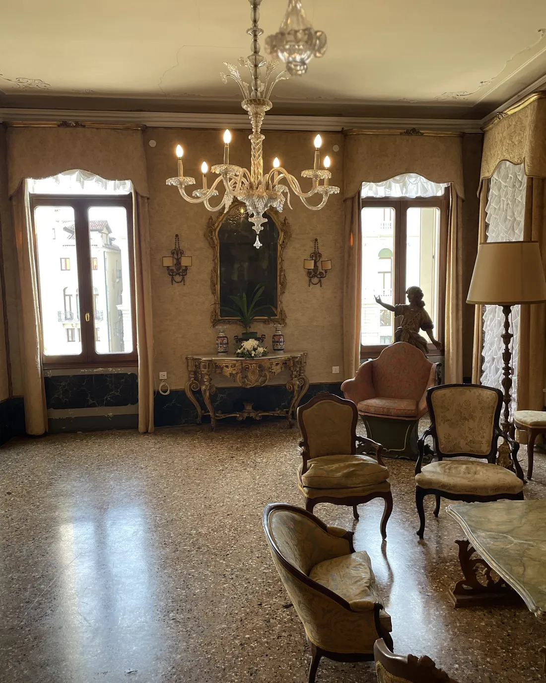 A side salon with a crystal chandelier, antique armchairs and windows onto the canal