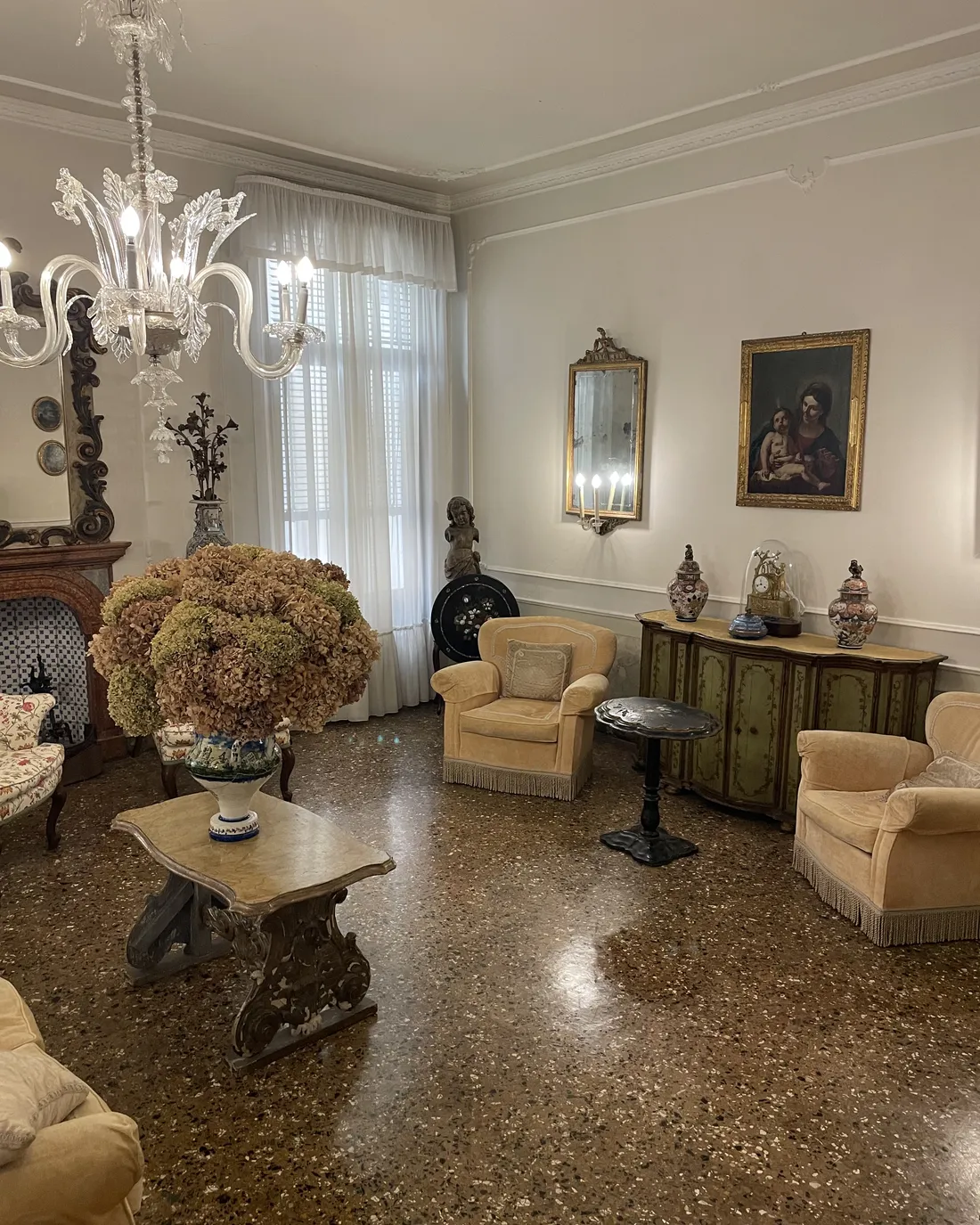 A bright side salon with a glass chandelier, armchairs and old paintings